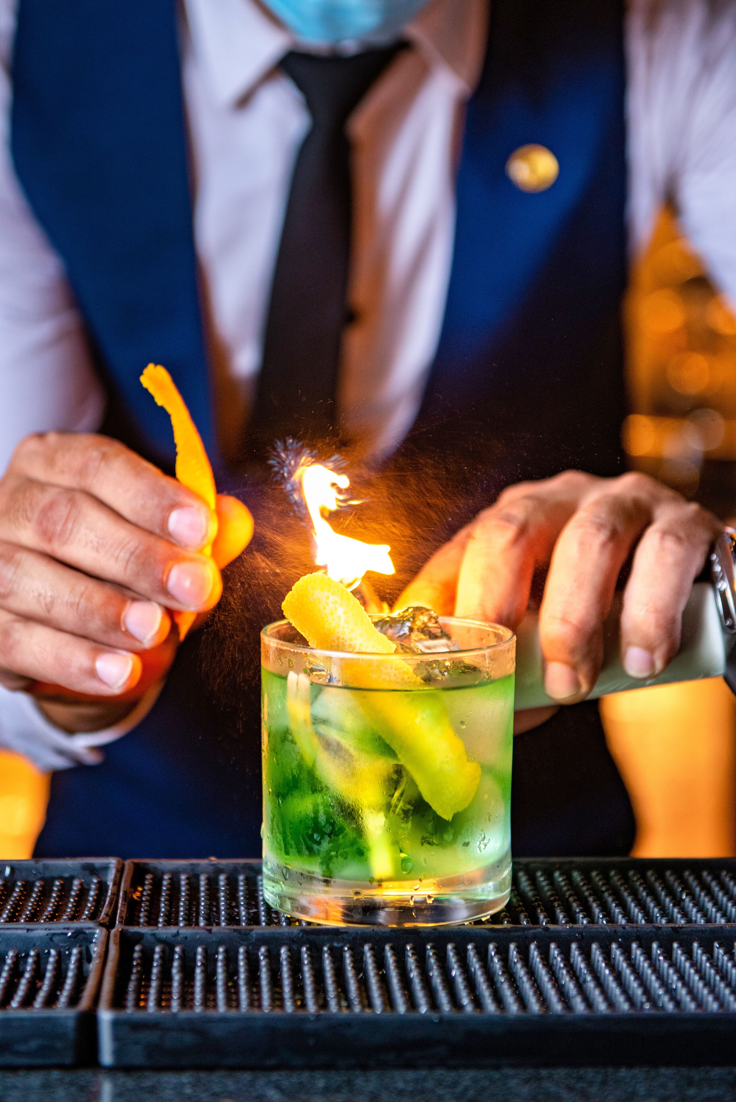 Un barman prépare un cocktail avec une bougie allumée.