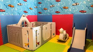 A play area with a playhouse, a slide, and a wall with a car pattern.