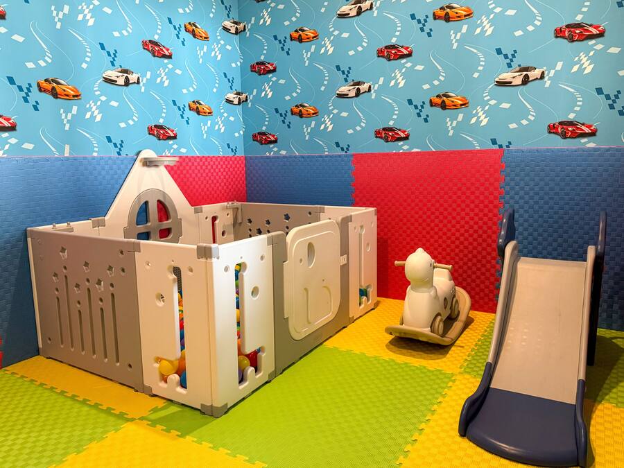 A play area with a playhouse, a slide, and a wall with a car pattern.