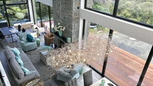 Un salon moderne avec un mur en pierre, de grandes fenêtres et une vue sur la verdure.