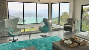 Un salon moderne avec de grandes fenêtres, un mur en pierre et une vue sur un lac.