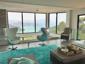 Enjoy breathtaking views of the coast from this spacious living room with a large window and comfortable seating area.