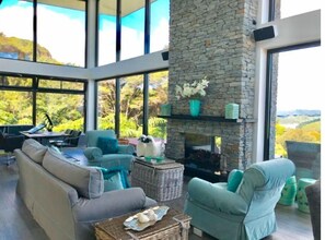 Enjoy expansive views of the surrounding landscape from the large windows in this room, featuring a cozy seating area with a sofa and armchairs.