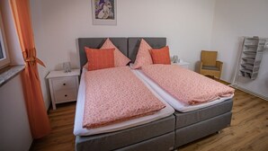 A double bed with a grey headboard, two bedside tables, and a small chair. - 4****Sterne Spatzennest 86 sqm between Augsburg and Ulm quietly located new building (Burtenbach)