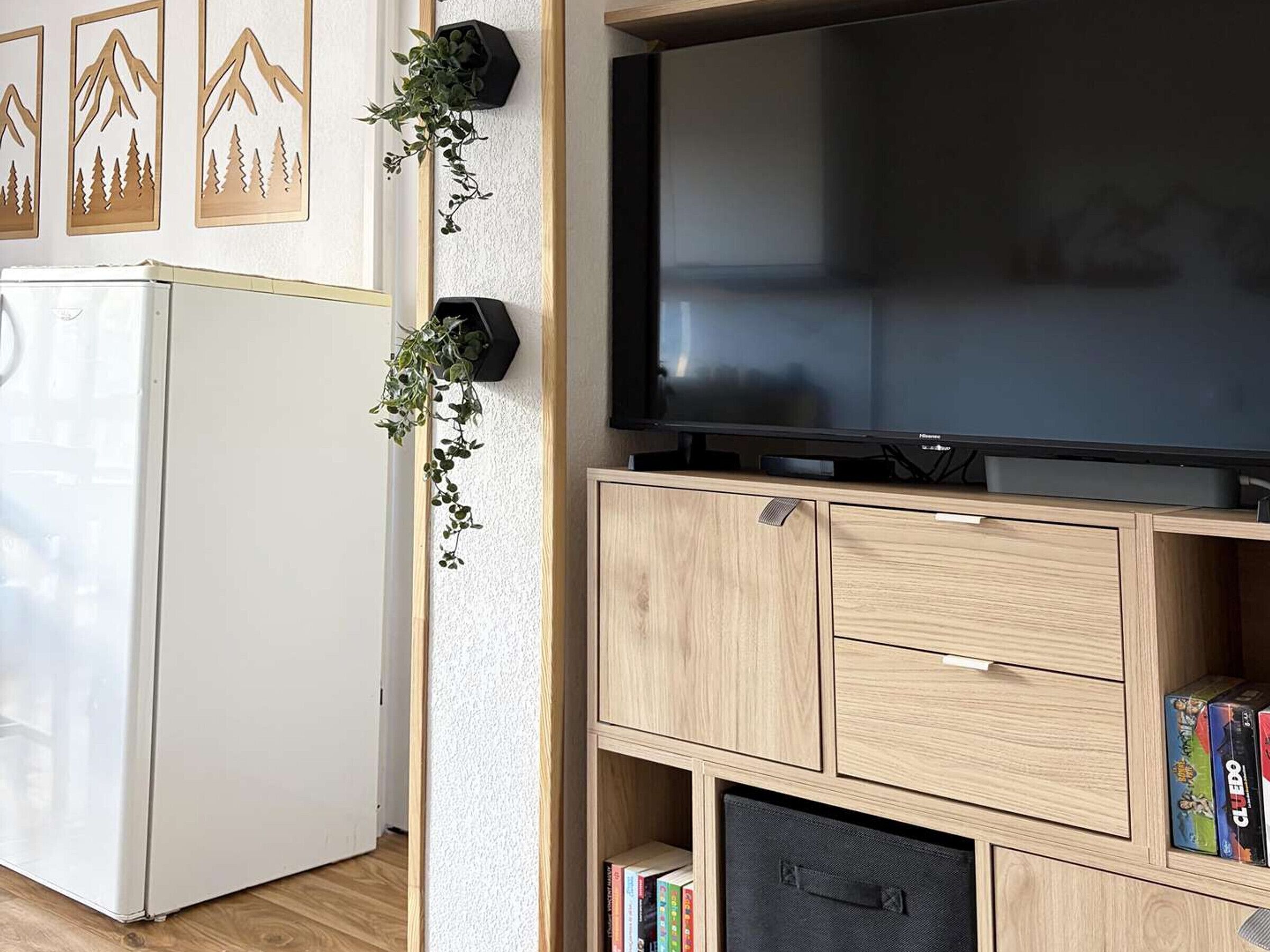 Ein Wohnzimmer mit einem Flachbildfernseher, Holzsäcken und einem weißen Kühlschrank.