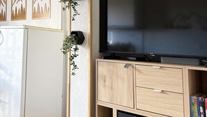 Un salon équipé d’un téléviseur à écran plat, de meubles en bois et d’un réfrigérateur blanc.