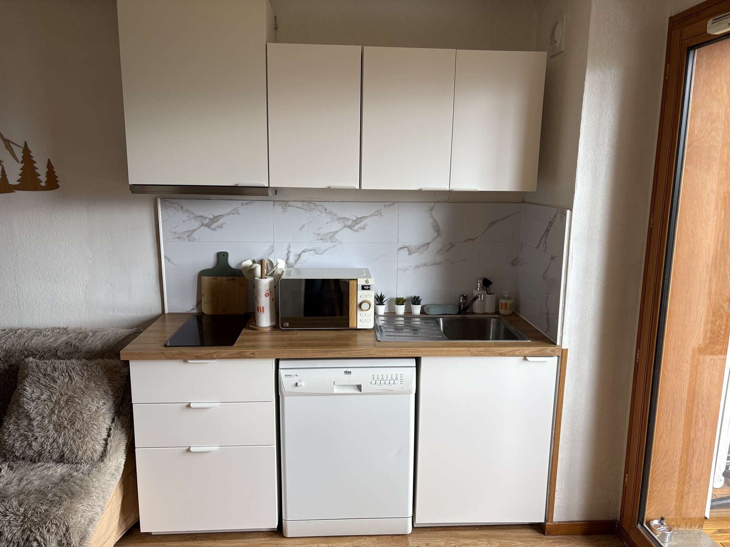 A compact kitchen with a microwave, dishwasher, and a sink.