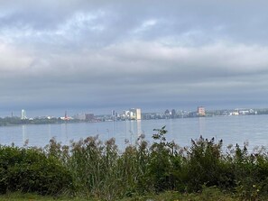 A cityscape with a river in the foreground and a cloudy sky.