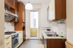 A compact kitchen with a stove, oven, microwave, and sink.