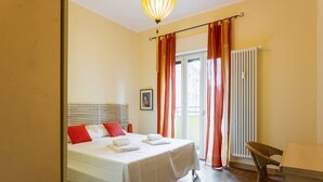 A hotel room with a bed, a chair, a table, and a window with curtains. - Hostmate - Milano - Sapeto- Colonne S.Lorenzo (Milano)