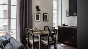 Een moderne keuken met donkere kastjes, een eettafel met stoelen en ingelijste foto's aan de muur.