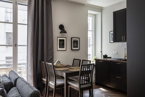 A modern kitchen with dark cabinetry, a dining table with chairs, and framed pictures on the wall.
