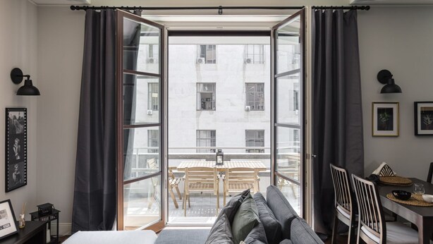 Een kamer met een bed, een slaapbank, een eettafel en uitzicht door een groot raam.