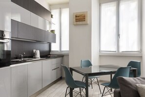 Een moderne keuken met een eethoek, witte kasten en een glazen tafel.