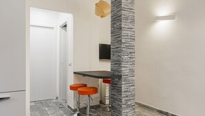 A modern kitchen with a bar area, a white door, and a textured column. - Hostmate - Milano - Filzi - Stazione Centrale (Milano)