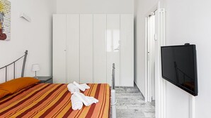 A hotel room with a bed, a TV, a wardrobe, and a radiator. - Hostmate - Milano - Filzi - Stazione Centrale (Milano)