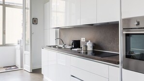 Una cocina moderna con armarios blancos, un horno de acero inoxidable y una cafetera.