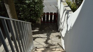 A staircase leading to a gated area with a tree and a white wall on one side. - Air-Conditioned Studio 4 Ppl in Le Grau-du-Roi (Le Grau-du-Roi)