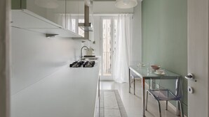 A modern kitchen with white cabinets, a glass dining table, and pendant lights. - Hostmate - Milano - Cenisio - Bullona (Milano)
