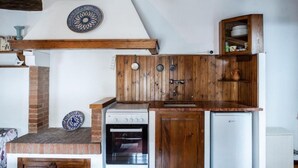 Une cuisine compacte équipée d’une cuisinière, d’un four et d’un réfrigérateur, de meubles en bois et d’une assiette décorative accrochée au mur.