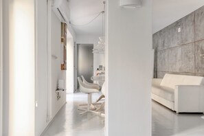 A modern living room with a white sofa, a dining area with white chairs, and a kitchen area with a white countertop. - Hostmate - Milano - Solferino - Brera (Milano)