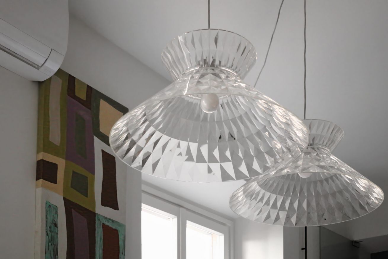 A room with a modern pendant light fixture, a large window, and a colorful abstract painting on the wall.