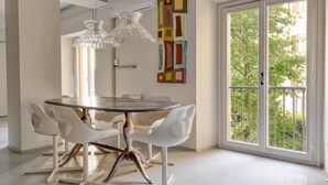 A dining area with a round table, white chairs, and pendant lights.