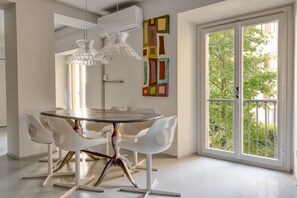 A dining area with a round table, white chairs, and pendant lights. - Hostmate - Milano - Solferino - Brera (Milano)