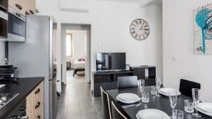 Eine moderne Küche mit Essbereich, einer Wanduhr und einem Fernseher im Hintergrund.