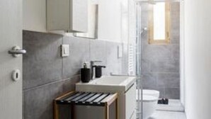 Ein modernes Badezimmer mit Dusche, Toilette und einer kleinen Waschtisch-Ecke.
