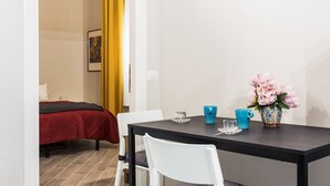 Una stanza con un letto, un tavolo con un vaso di fiori e una tazza blu.