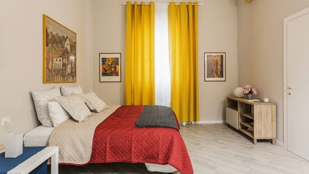 Una camera da letto con un letto, un comodino, un armadio e due quadri appesi al muro.