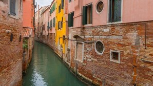 Un canale stretto affiancato da edifici storici con muri in mattoni a vista e finestre tradizionali.