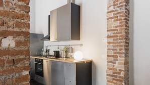 Eine kompakte Küche mit integriertem Backofen, Edelstahl-Schränken und einer abgehängten Küchenutensilienstange.