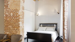 Ein Schlafzimmer mit einem hölzernen Bett, einer Ziegelwand und einem Sessel.