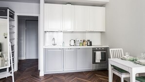 A modern kitchen with white cabinets, a built-in oven, and a dining area with a white table and chairs. - Hostmate - Milano - Freguglia's Studio - Guastalla (Milano)