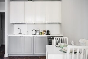 A kitchen with white cabinets, a white countertop, and a dining table with chairs. - Hostmate - Milano - Freguglia's Studio - Guastalla (Milano)
