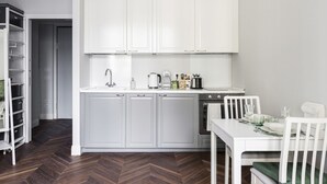 A modern kitchen with white cabinets, a built-in oven, and a dining area with a white table and chairs. - Hostmate - Milano - Freguglia's Studio - Guastalla (Milano)