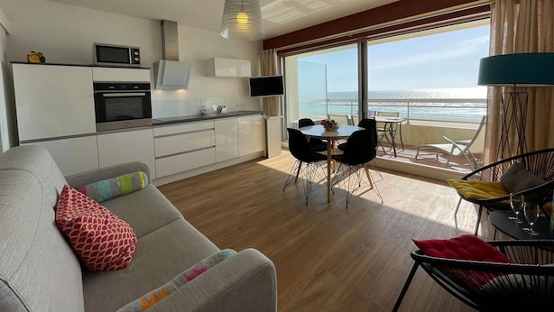 Een moderne keuken met een eethoek en een balkon met uitzicht op zee.