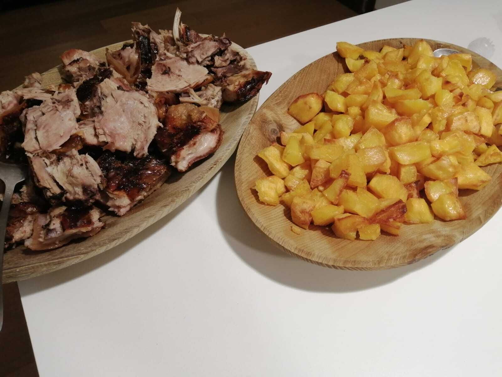 Une planche à découper en bois avec de la viande tranchée et des pommes de terre coupées en dés.