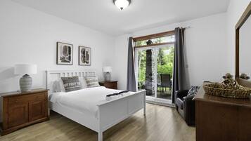 Quarto com cama, mesas de cabeceira, penteadeira e janela com cortinas.