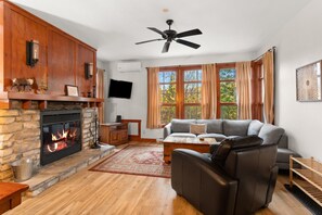 Una sala de estar con chimenea, un sofá, una mesa de centro y un televisor montado en la pared.