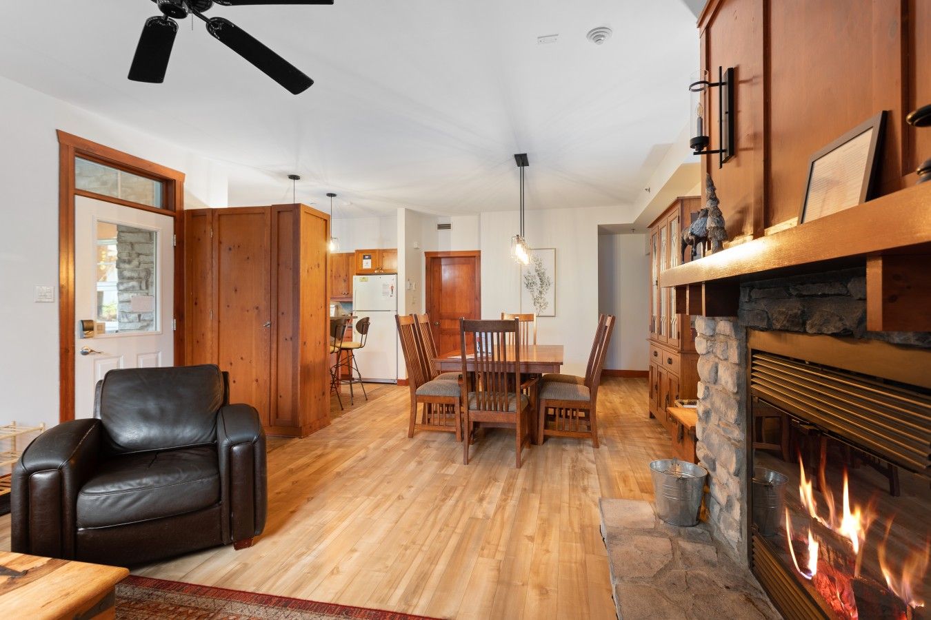 A cozy living room with a fireplace, wooden dining table, and a leather chair.