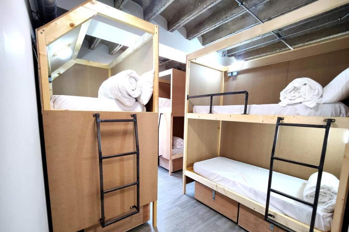 A dormitory room with bunk beds, a ladder, and a small desk.