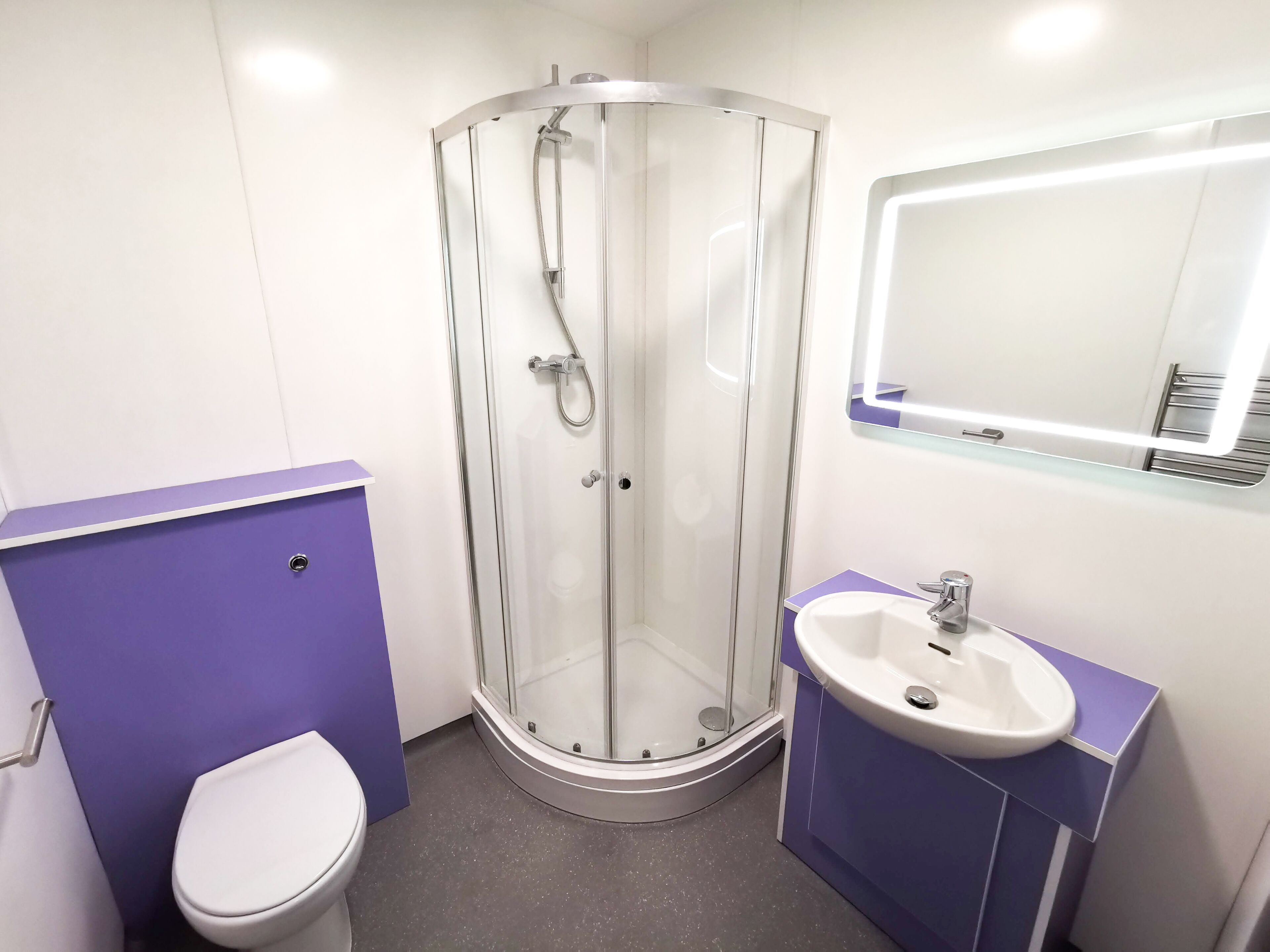 Une salle de bain avec une douche à parois de verre, des toilettes blanches et un lavabo avec un miroir au-dessus.