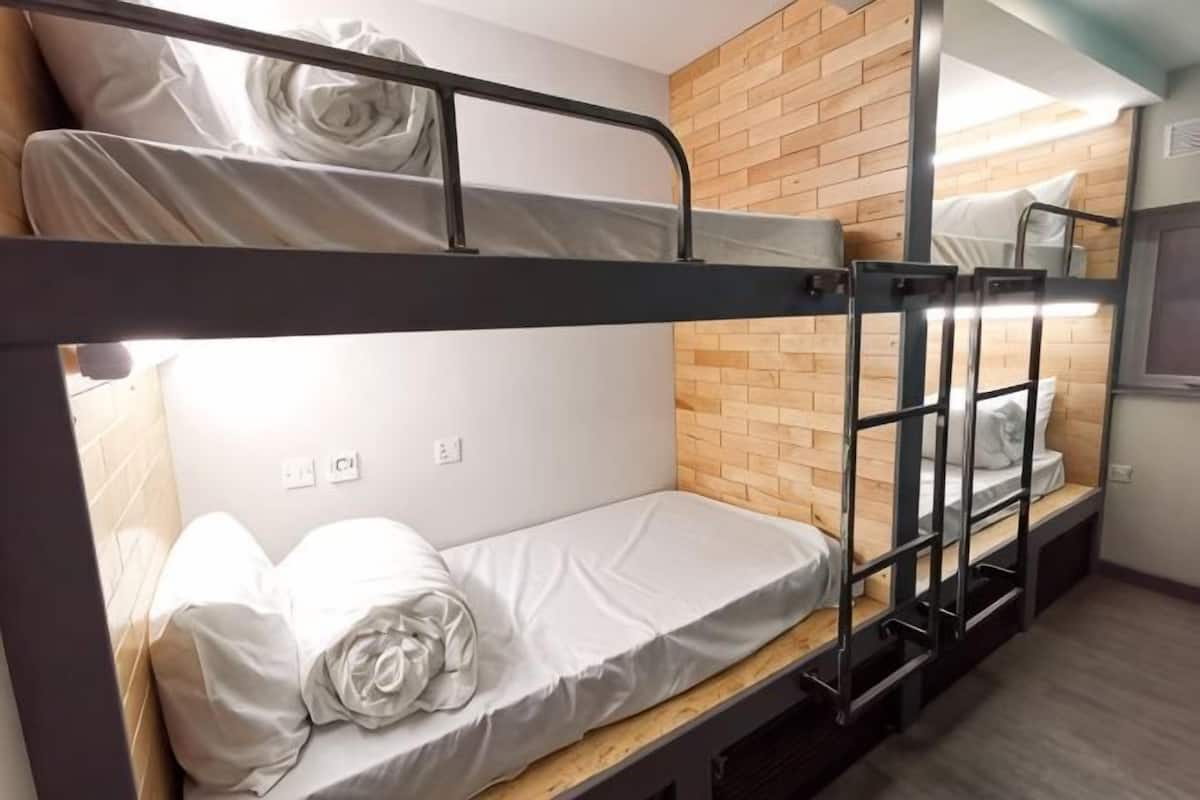 A bunk bed room with a wooden wall, a window, and a power outlet.