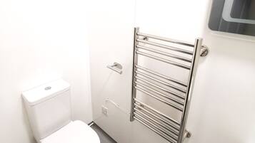 Un baño pequeño y moderno con inodoro, toallero y espejo.