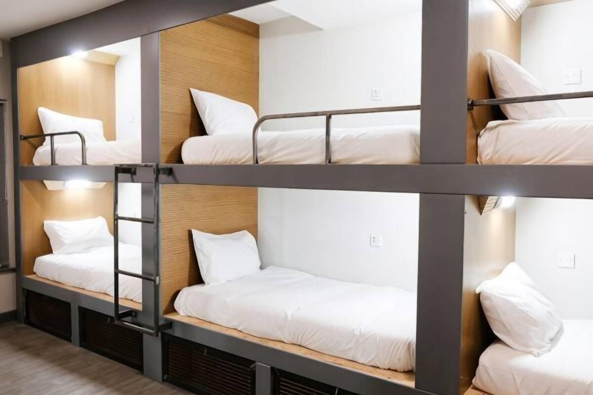 A bunk bed room with a ladder, wooden panel wall, and white bedding.