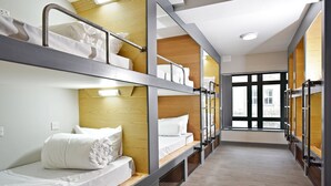 Une chambre d’hôtel avec des lits superposés, un lambris en bois et une grande fenêtre donnant sur l’extérieur.