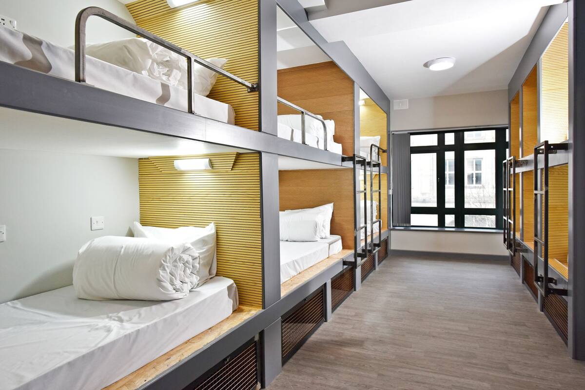 A hotel room with bunk beds, wooden paneling, and a large window providing a view of the outside.